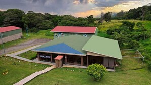 A building with a green roof, a reception area, and a covered outdoor seating area. - Nafre House (Monteverde)