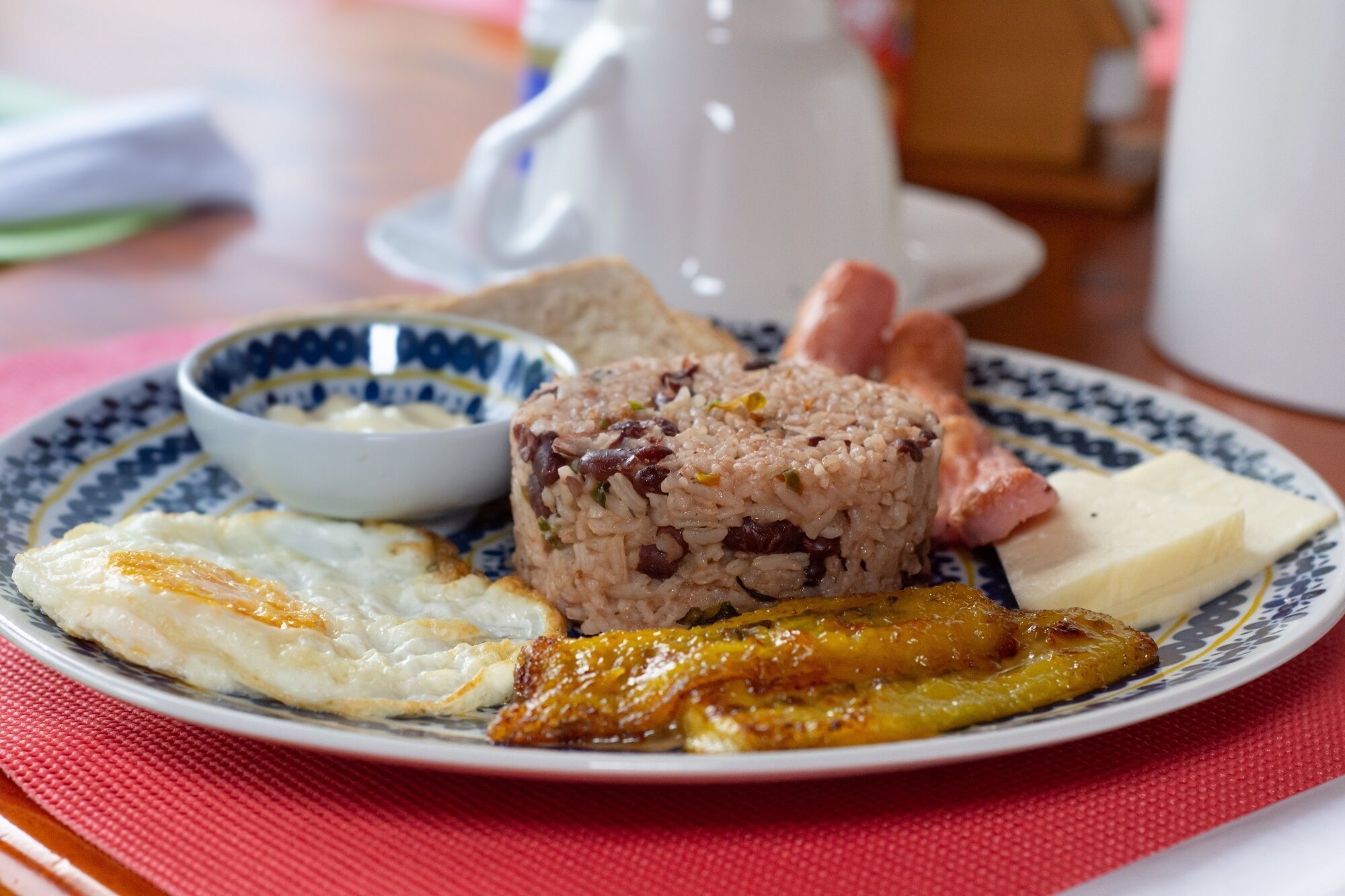 A plate with rice, eggs, ham, and fried plantains.