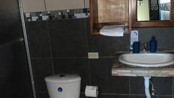 Un baño con inodoro, lavamanos, espejo y toallero.