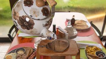 A table with a floral teapot, a cup, and various breakfast items.