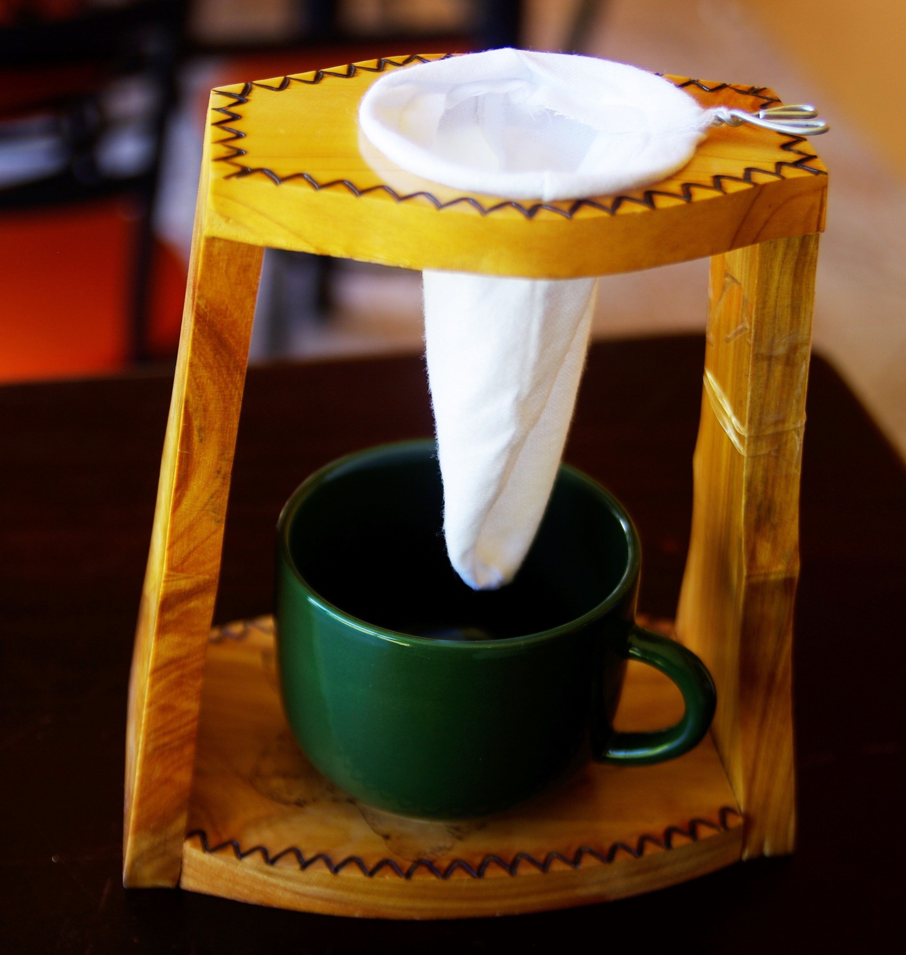 A green mug with a white napkin dispenser on a wooden coaster.