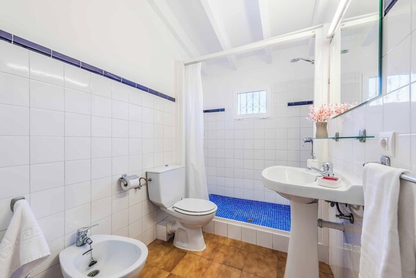 A bathroom with a toilet, bidet, sink, and a bathtub with blue mosaic tiles. - Can Patricia - Four Bedroom Villa, Sleeps 8 (Pollença)