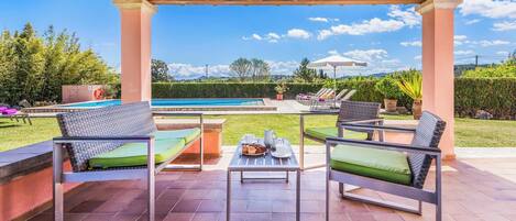 Ein überdachter Außenbereich mit Pool, Liegestühlen und einem Tisch mit Getränken und Snacks.