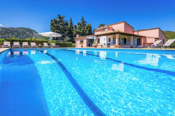 A clear blue swimming pool with lounge chairs and a building with a tiled roof in the background. - Can Patricia - Four Bedroom Villa, Sleeps 8 (Pollença)