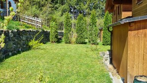 Una cabaña de madera con un muro de piedra y un patio cubierto de césped.