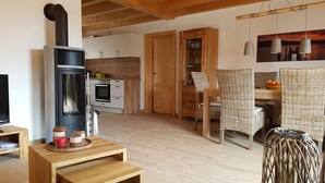 Una cocina acogedora con estufa de leña, armarios de madera y un comedor con sillas de mimbre y una mesa.