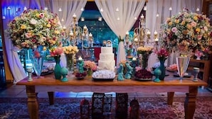Una zona de recepción decorada con arreglos florales, un pastel de varios niveles y una araña.