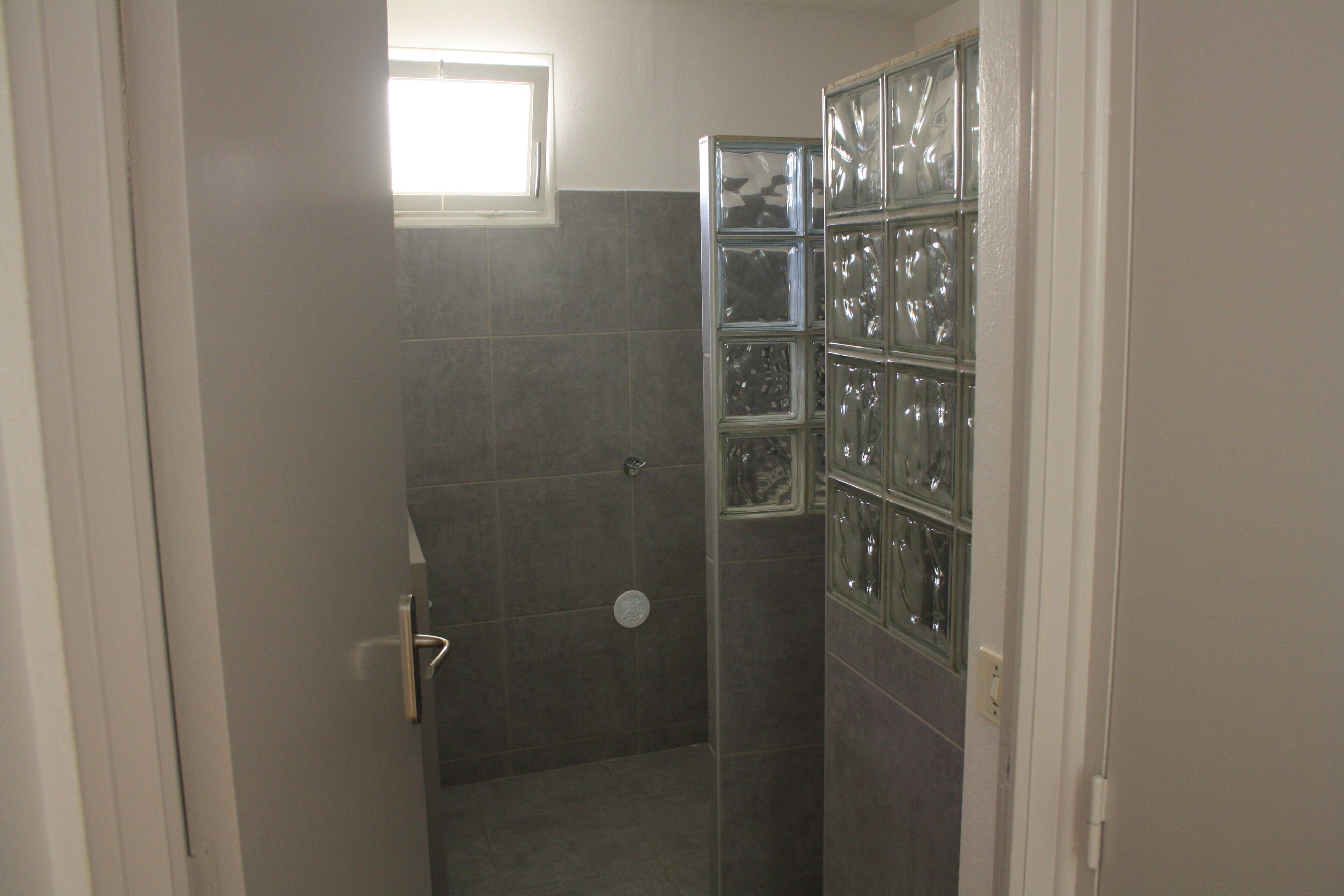 A shower with a glass enclosure and a window above it.