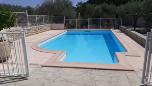 Une piscine rectangulaire entourée d’une terrasse en pierre.