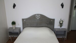 Une chambre à coucher avec une tête de lit en bois, deux tables de chevet avec des lampes, une petite plante en pot et un vase avec des fleurs.