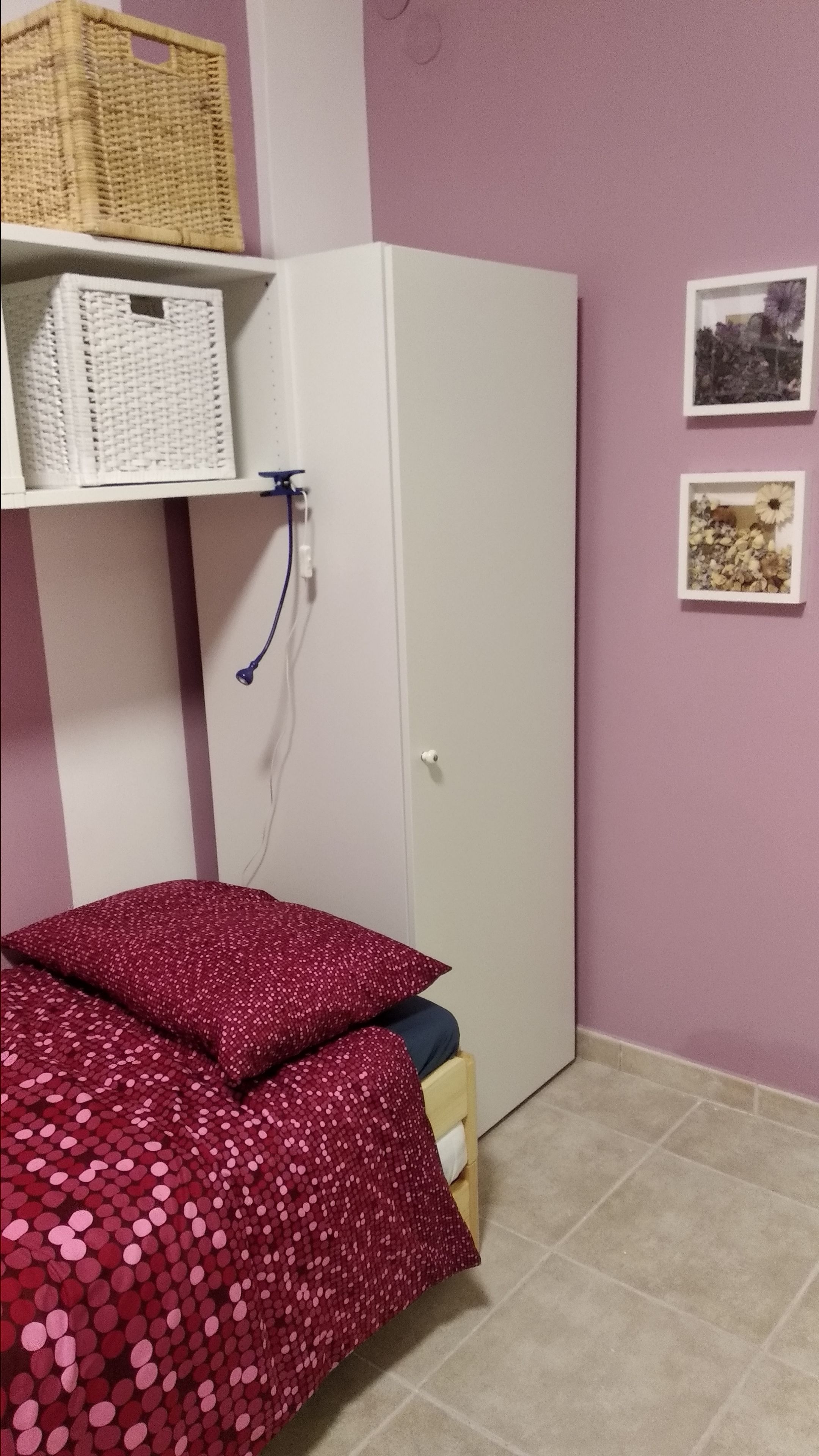 Une chambre à coucher avec un lit, une armoire et une étagère sur laquelle se trouve un panier.