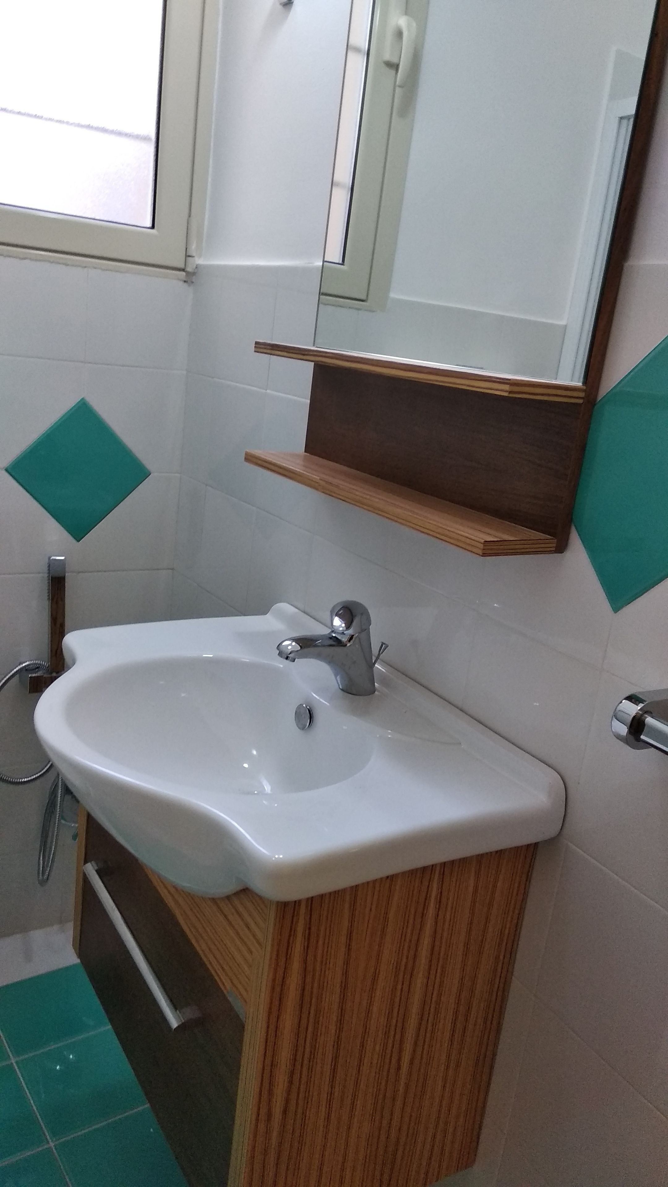 Un baño con lavamanos blanco, tocador de madera y un espejo encima.
