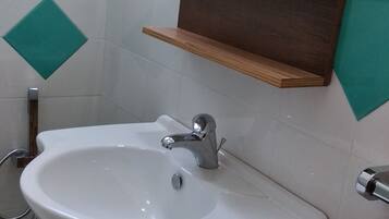Un baño con lavamanos blanco, tocador de madera y un espejo encima.