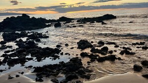 Une plage parsemée de formations rocheuses et de traces de pas dans le sable.