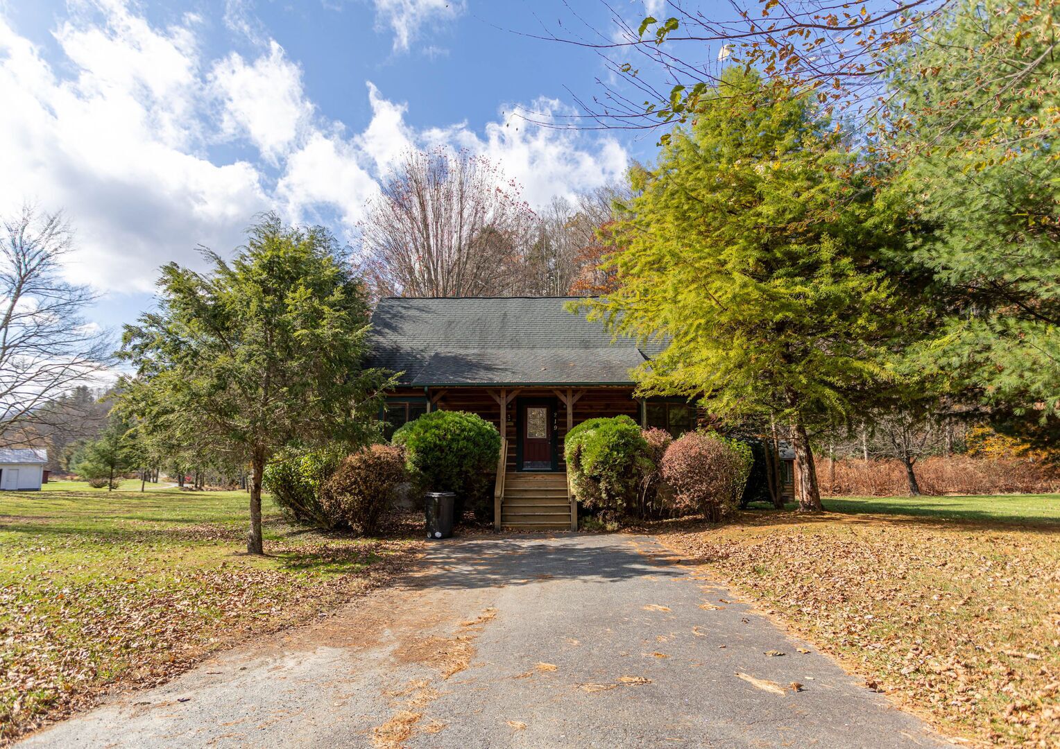 A lodge with a covered front porch, a small attached garage, and a well-maintained lawn.