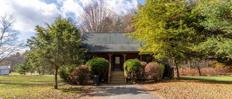 A lodge with a covered front porch, a small attached garage, and a well-maintained lawn.
