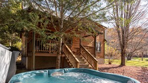 A hot tub in a backyard with a wooden deck and stairs leading to a cabin. - Baird's Creek Cabin  Cozy Cabin, Close to Golf, Creekside (Vilas)