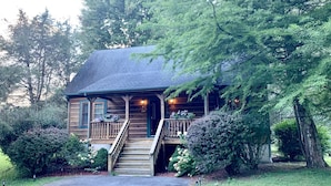 A wooden cabin with a porch, stairs, and a small garden area. - Baird's Creek Cabin  Cozy Cabin, Close to Golf, Creekside (Vilas)