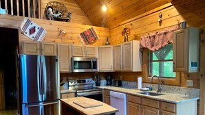 A wooden cabin-style kitchen with a stainless steel refrigerator, microwave, stove, and dishwasher. - Baird's Creek Cabin  Cozy Cabin, Close to Golf, Creekside (Vilas)