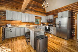 Eine geräumige Küche mit Holzböden, Granit Arbeitsplatten und Edelstahlgeräten.