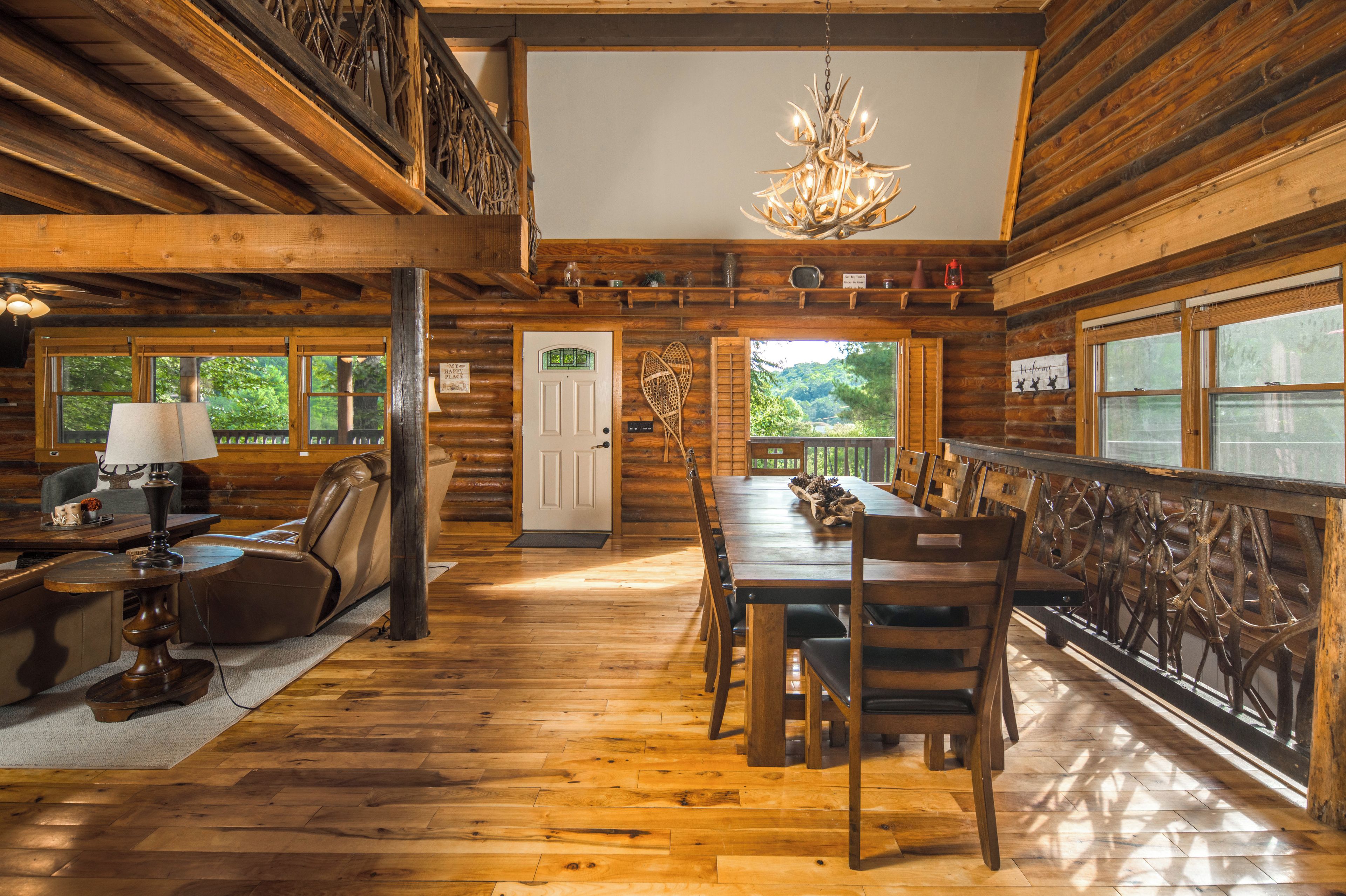 Interior de una cabaña de troncos con comedor, sillón de masaje y candelabro.