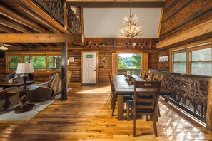 Ein Blockhaus-Interieur mit Essbereich, Massagesessel und einer Pendelleuchte.