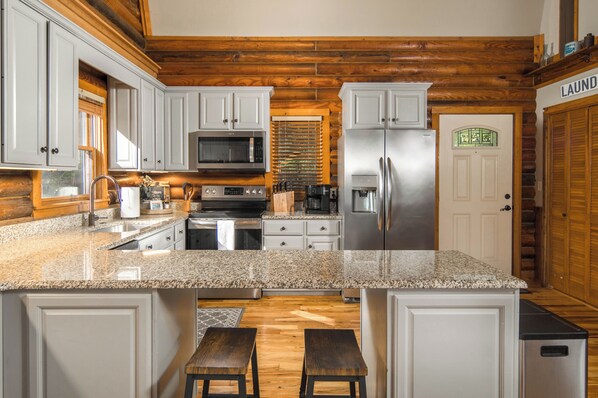 A kitchen with granite countertops, stainless steel appliances, and wooden cabinetry.
