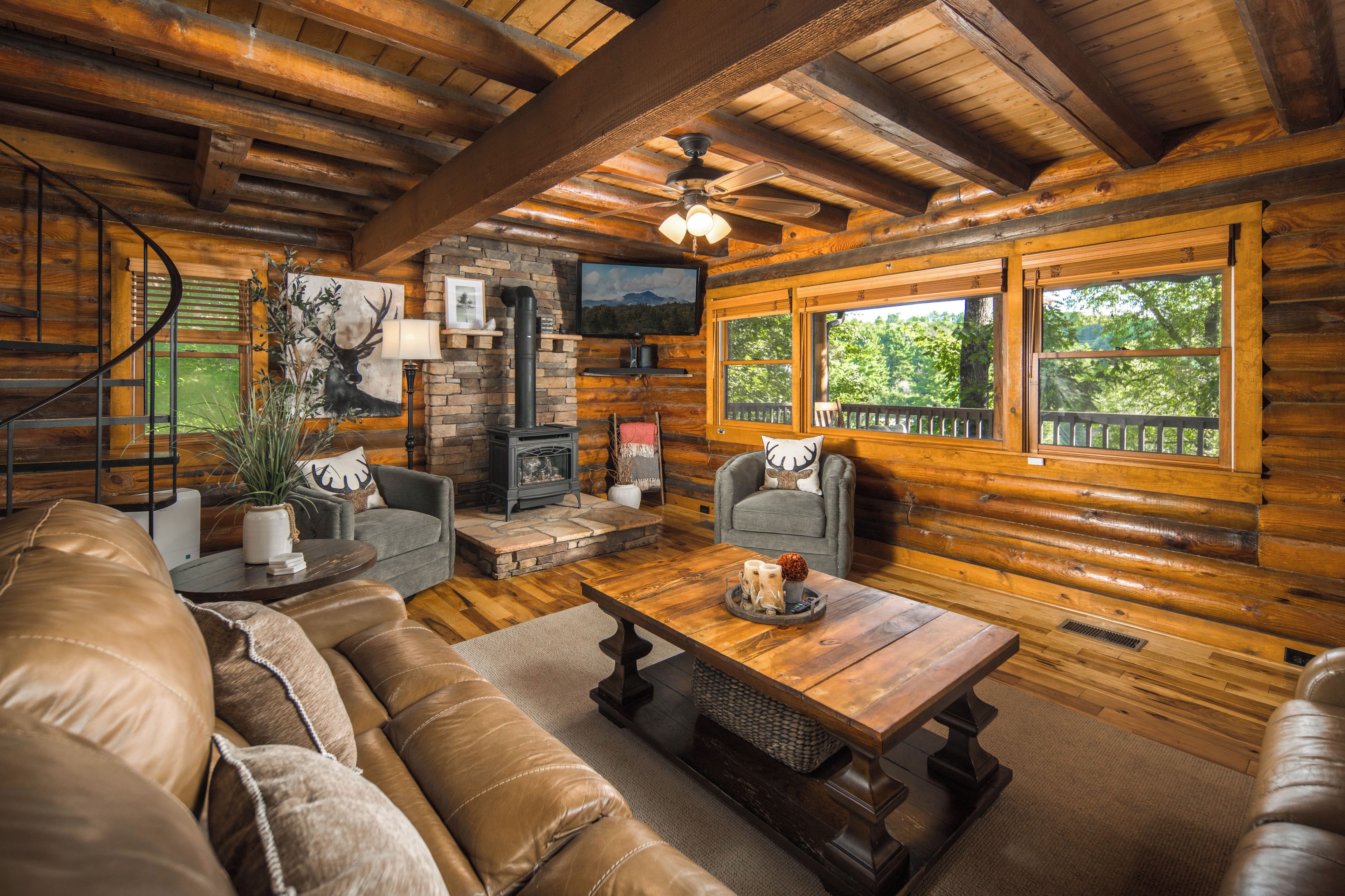 A log cabin interior with a fireplace, a sofa, a coffee table, and a television.