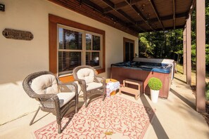 A covered patio area with wicker chairs, a hot tub, and a wooden sign indicating a retreat location.
