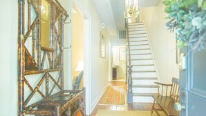 Una scala che conduce a un secondo piano, una panca di legno e uno specchio con motivo geometrico.