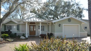 A single-story house with a front porch, a garage, and a driveway. - Cozy Waterfront Home with private dock, and access to the intercoastal waterway. (Palm Harbor)