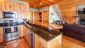 A spacious kitchen with wooden cabinets, stainless steel appliances, and a large island. - Large Cabin Sitting at 4,000 Feet Elevation (Zionville)