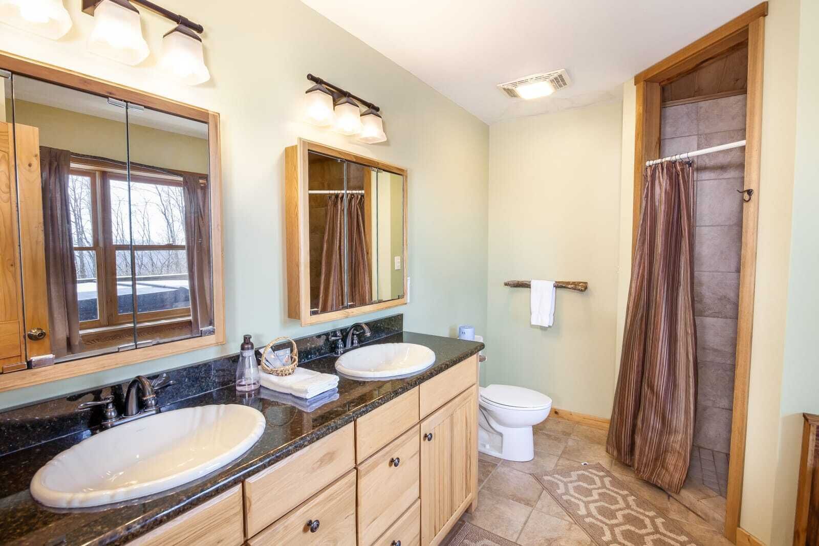 A bathroom with two sinks, a toilet, and a shower.