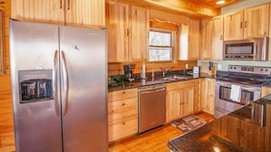 A kitchen with wooden cabinets, stainless steel appliances, a refrigerator with a water dispenser, a dishwasher, a microwave, and an oven. - Large Cabin Sitting at 4,000 Feet Elevation (Zionville)