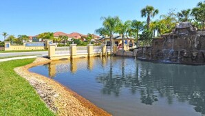 A water feature with a bridge, palm trees, and a building labeled "Paradise Palms" in the background. - Beautiful Town Home in Gated Community with Extensive Facilities (Kissimmee)