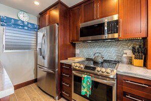 A modern kitchen with wooden cabinets, stainless steel appliances, a microwave, and a stove.