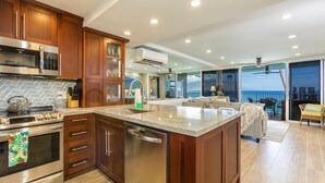 Uma cozinha moderna com uma ilha grande, eletrodomésticos de aço inoxidável e vista para o oceano.