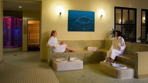 A spa area with two soaking tubs, a wall-mounted painting, and a reception desk. - aktiv Sporthotel (Pirna)