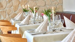 A restaurant setting with tables set for dining, featuring white tablecloths, clear glassware, and decorative napkins. - aktiv Sporthotel (Pirna)