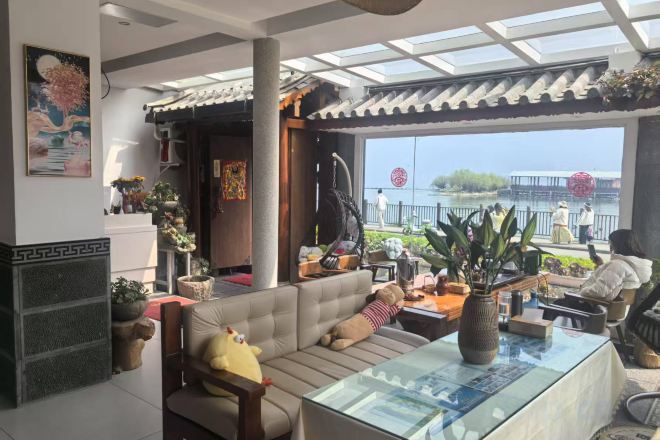 A modern living room with a sofa, a glass coffee table, and a view of the outdoors.