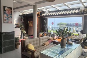 A modern living room with a sofa, a glass coffee table, and a view of the outdoors. - Dali Haitian Yihaijing Inn (Dali City)