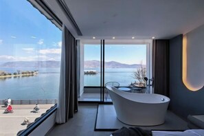 A modern room with a large window overlooking a body of water, a bathtub, and a dining area. - Dali Haitian Yihaijing Inn (Dali City)