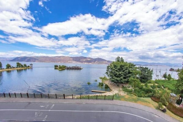 Un lago con un muelle, rodeado de vegetación y montañas al fondo.
