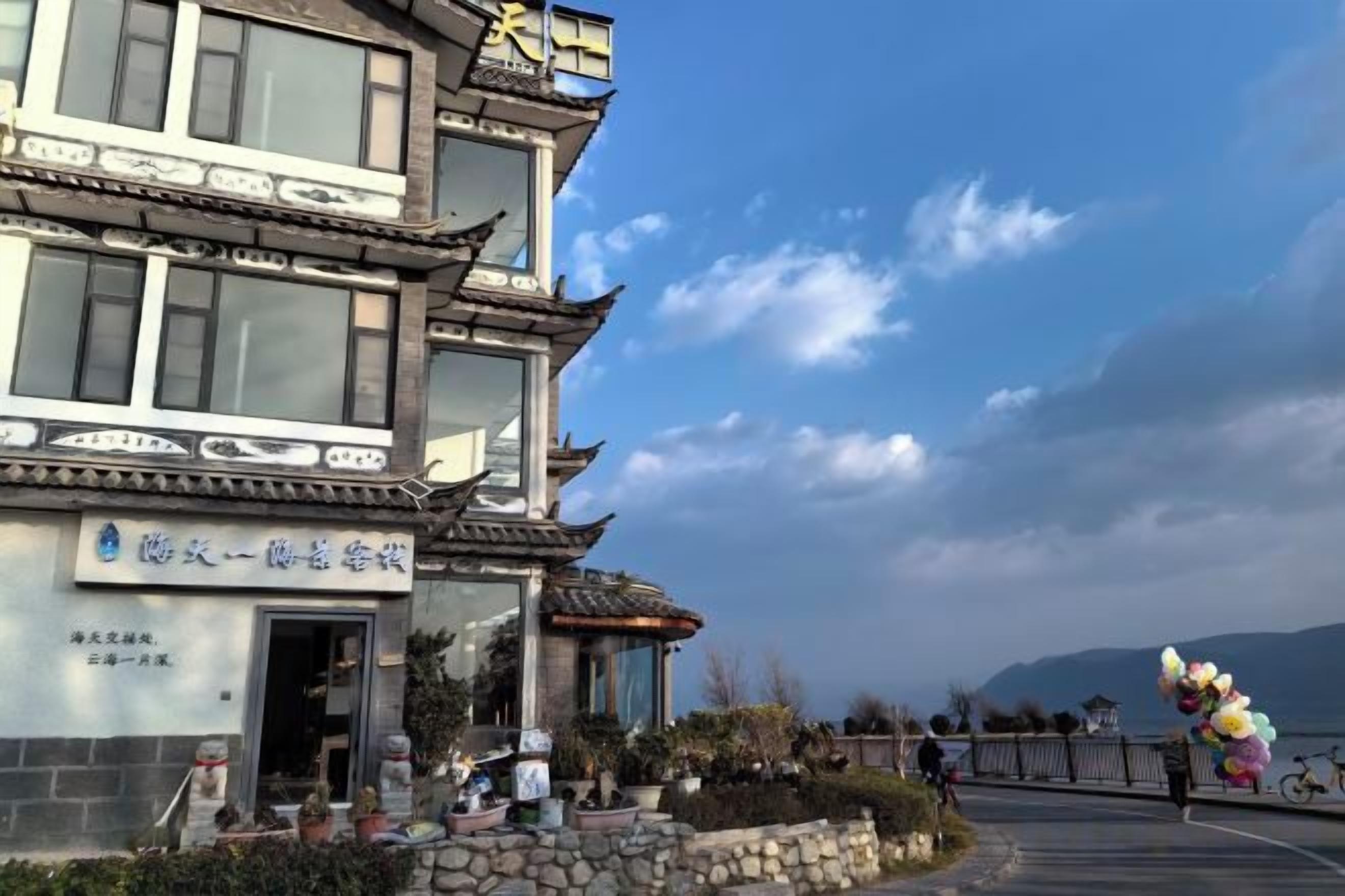 A traditional building with a sign, a stone pathway, and a view of the sea.