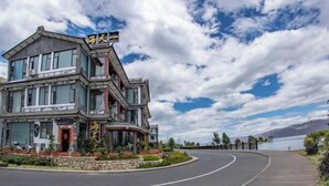 A multi-story hotel with a curved driveway, large windows, and a view of the lake. - Dali Haitian Yihaijing Inn (Dali City)