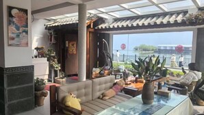 A room with a sofa, a glass table, and a view of a body of water. - Dali Haitian Yihaijing Inn (Dali City)