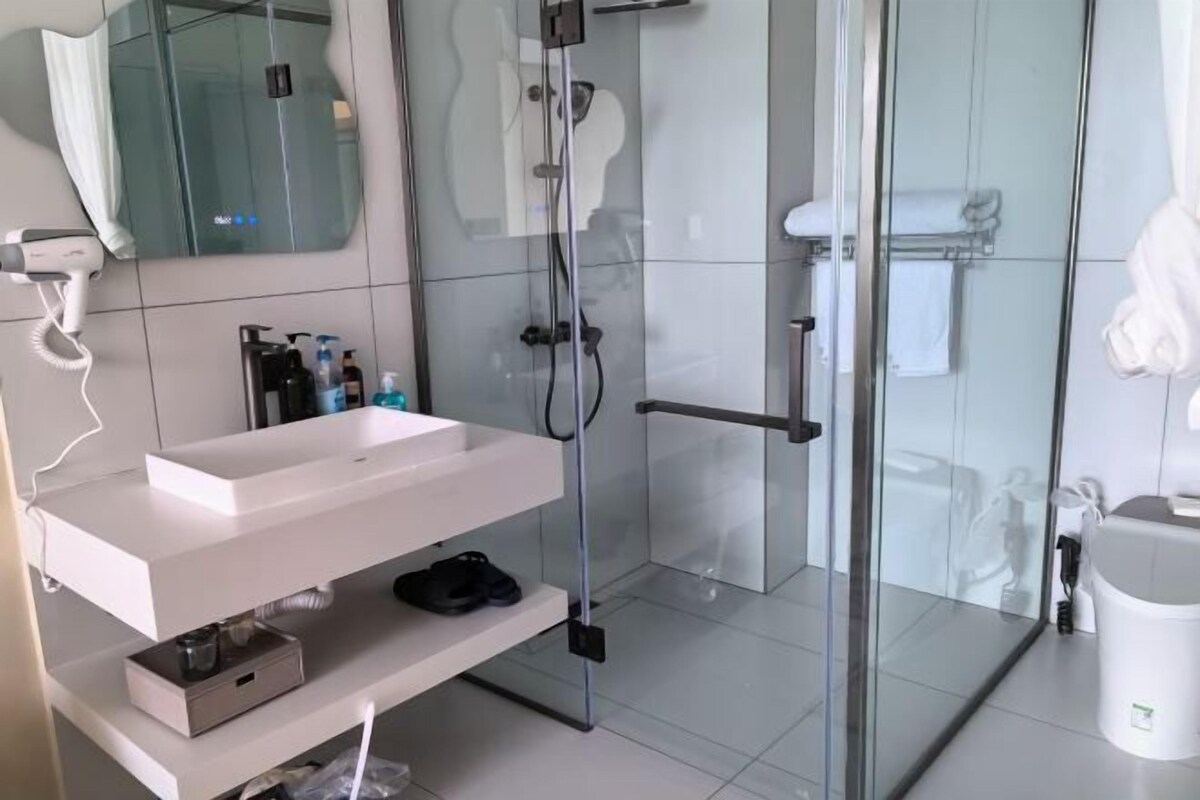 A modern bathroom with a glass shower enclosure, a white sink, and a mirror above it.