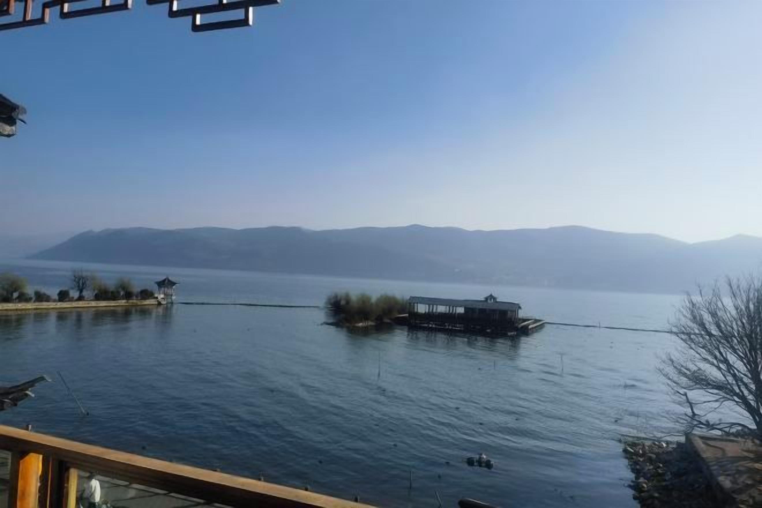 A calm lake with a boat and distant mountains.
