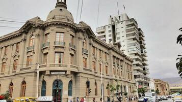 Un edificio histórico con una cúpula destacada y arquitectura clásica, situado en una calle concurrida junto a edificios modernos.