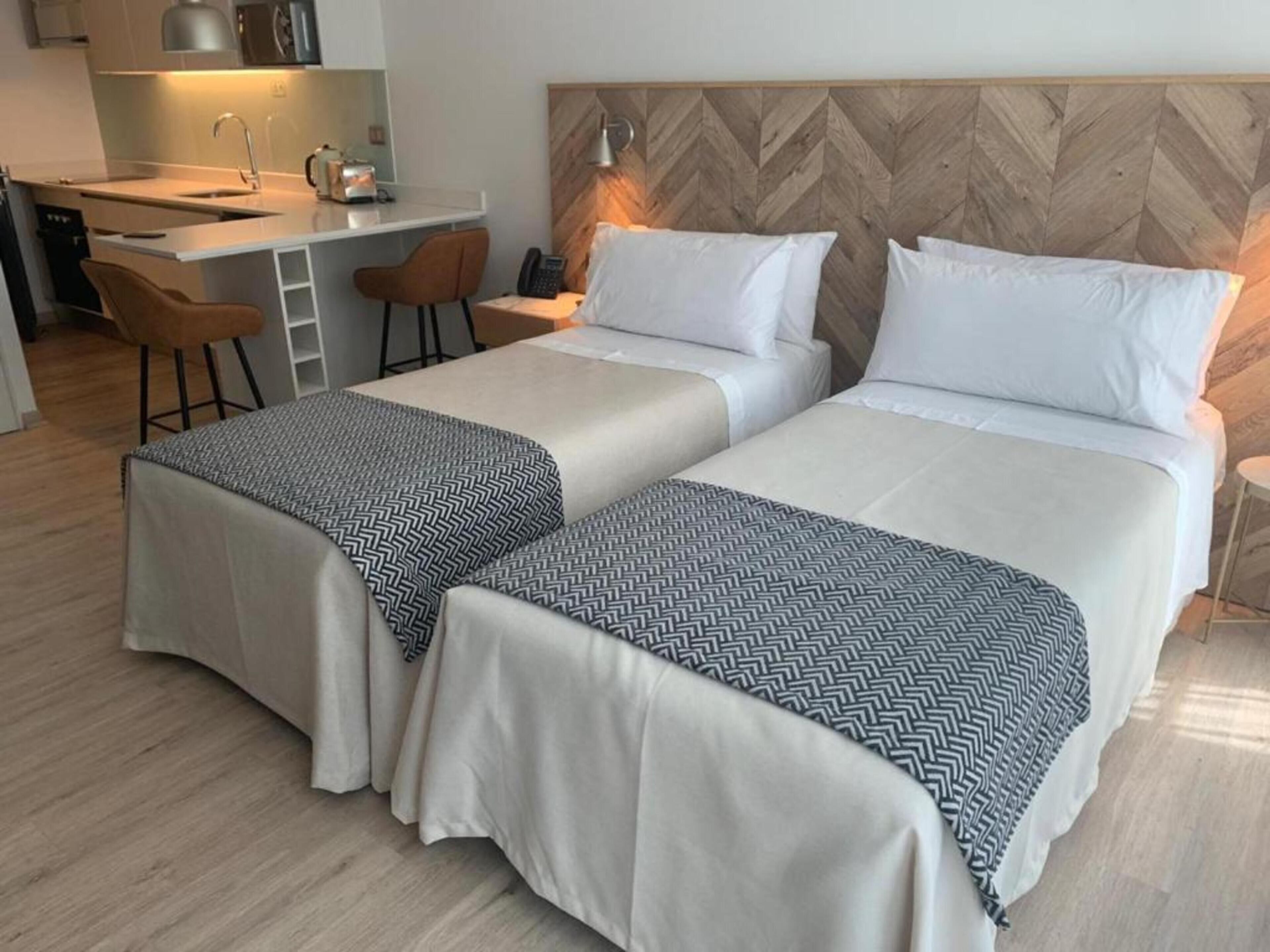 Habitación de hotel con dos camas, un escritorio y un rincón americano.